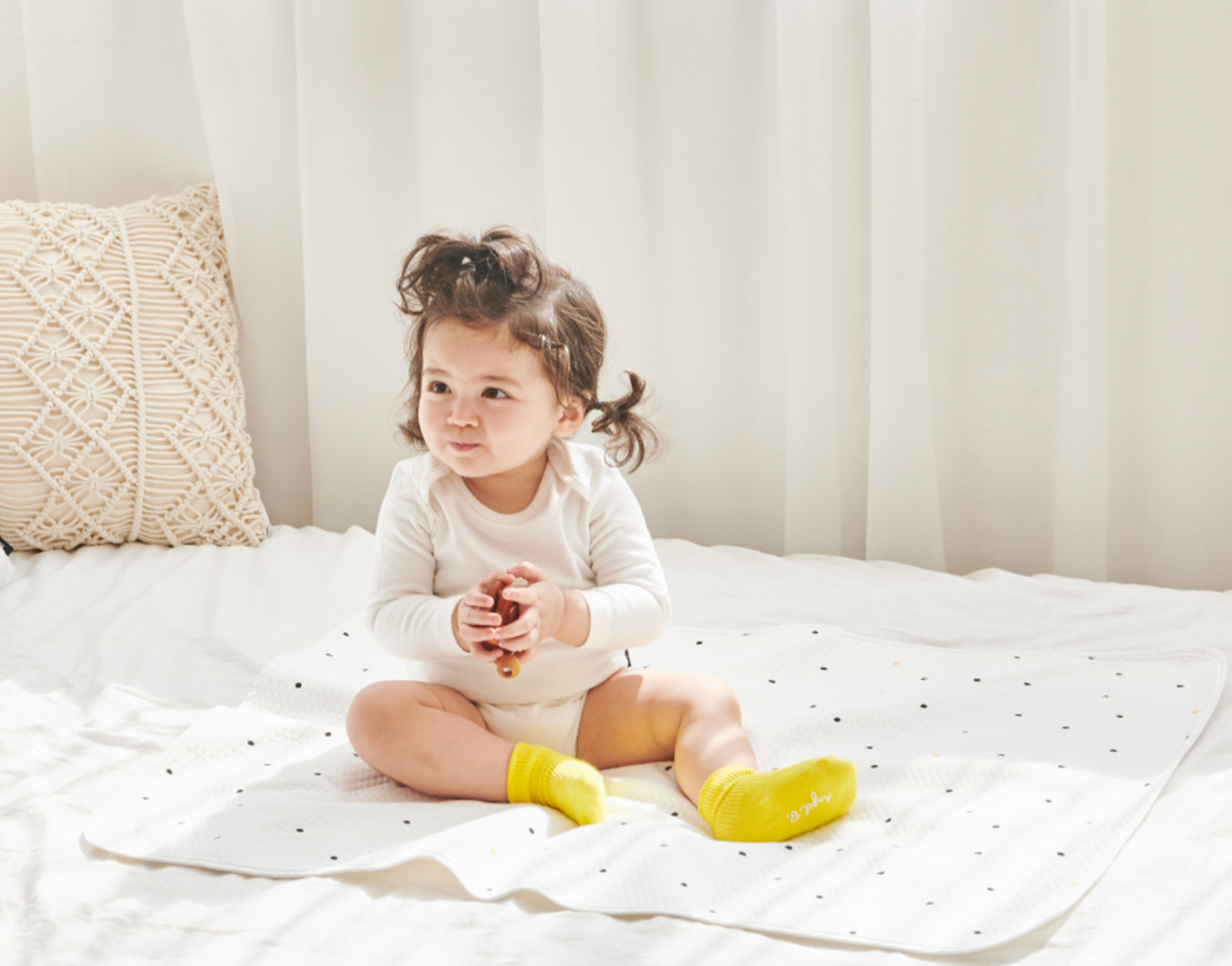 Baby sitting on Little Dot Waterproof Mattress Diaper Changing Mat in a well-lit room