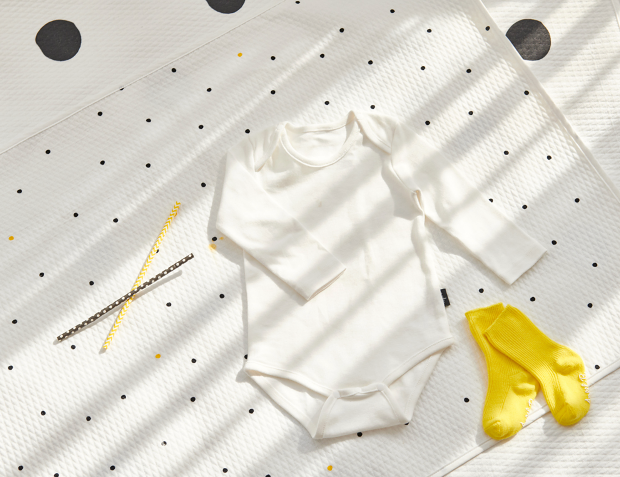 Little dot waterproof mattress (diaper changing mat) with white baby onesie and yellow socks, made in Korea, 100% cotton and polyester.